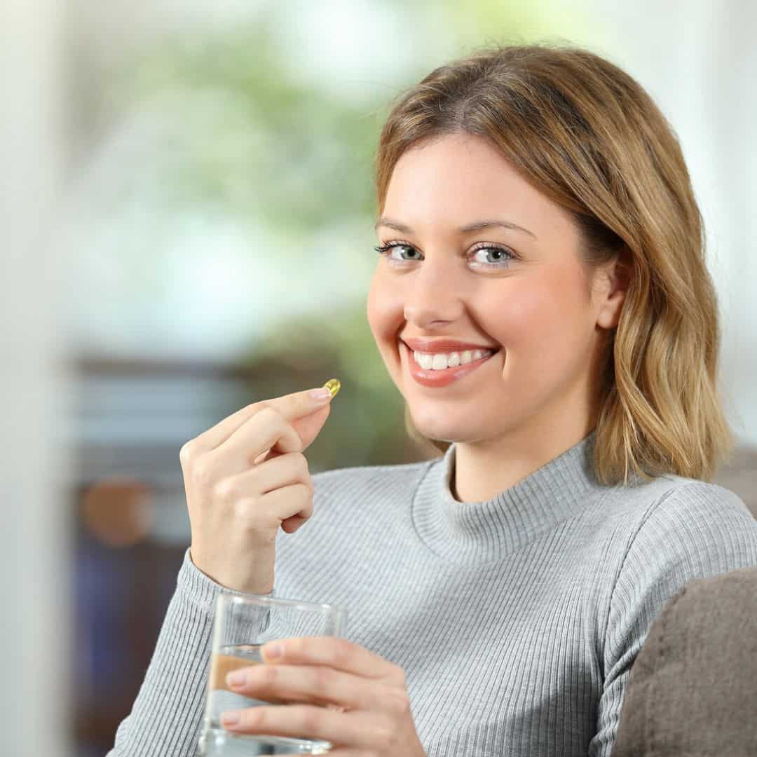 a woman taking omega 3 capsule