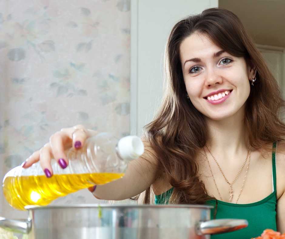 woman pouring cooking oil into a pot on a heated stove