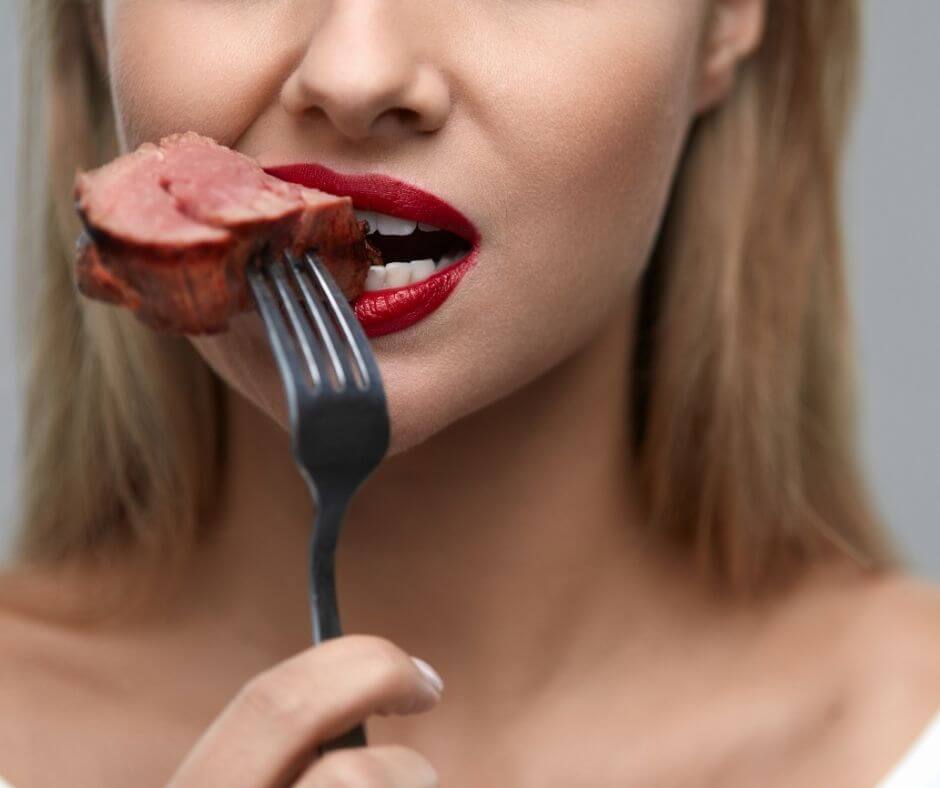 a woman eating a piece of meat