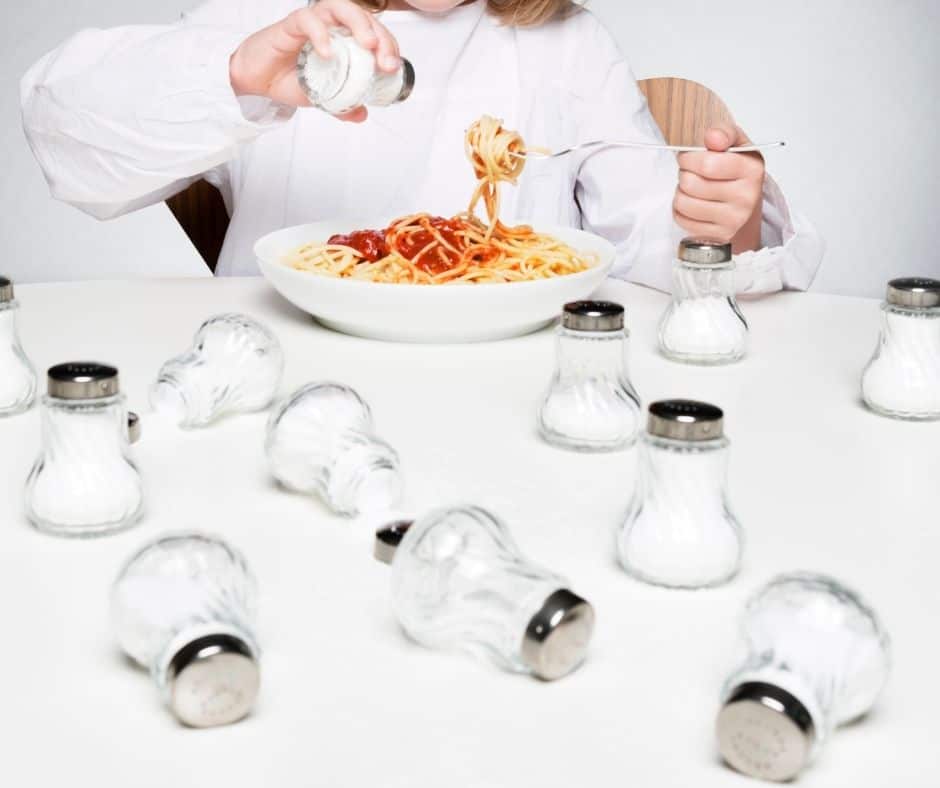a woman is adding salt to her food
