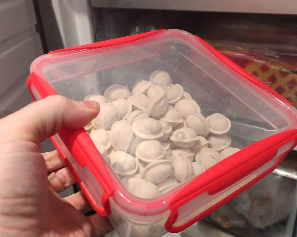 putting dumplings in the freezer in a plastic container
