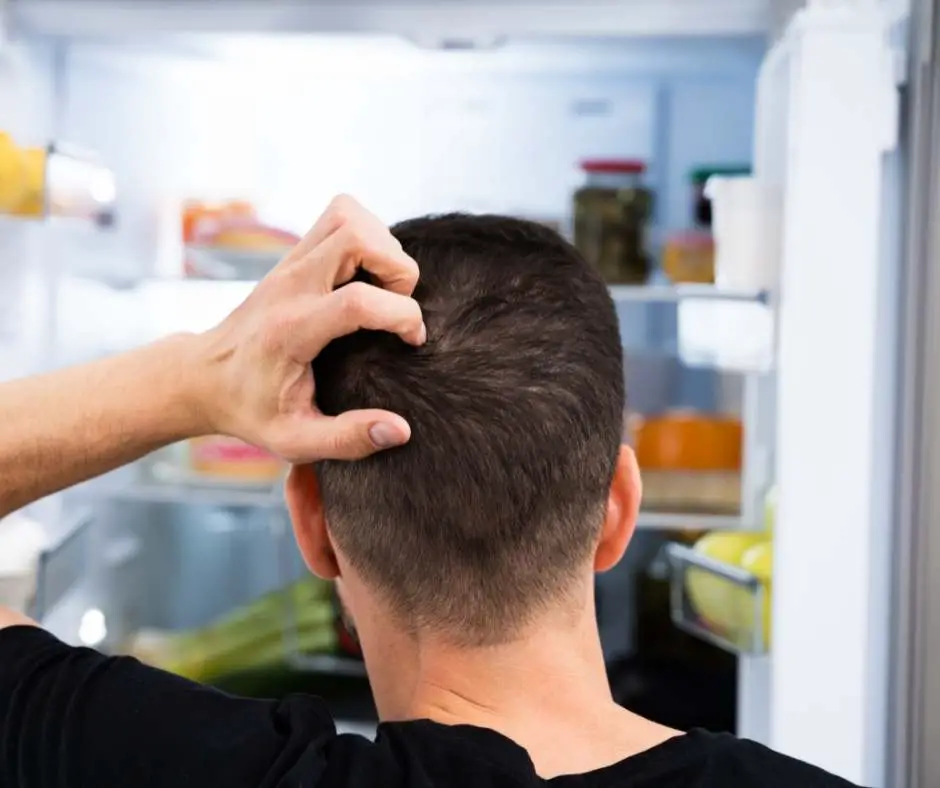 a man keeping the fridge door open for a long time