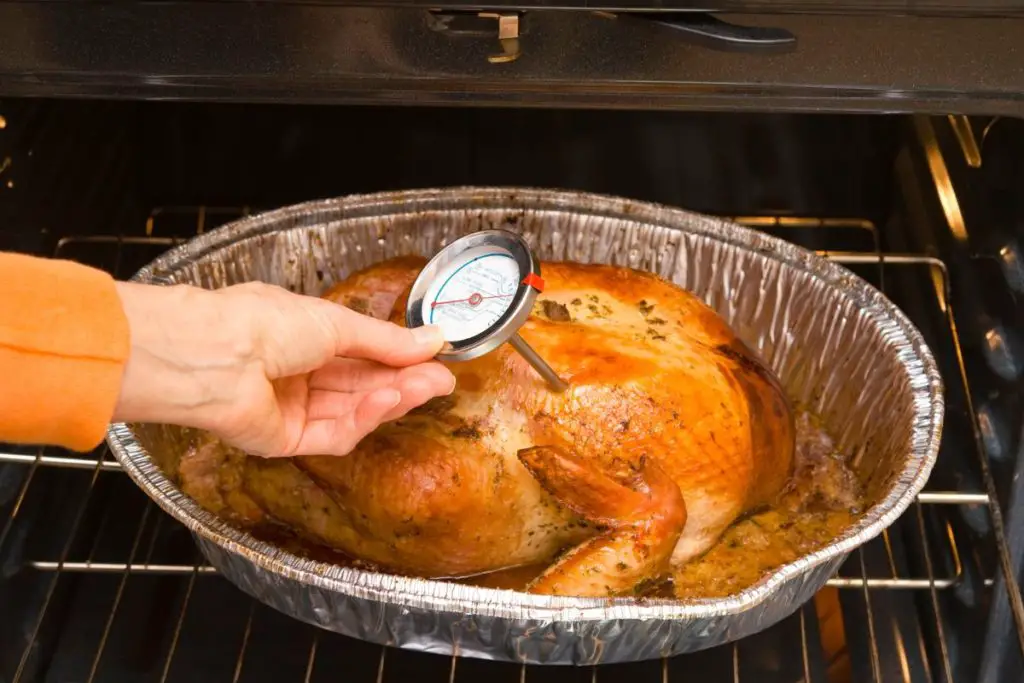 checking if the whole chicken is cooked with a thermometer