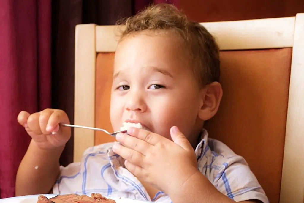 a boy is eating canned salmon