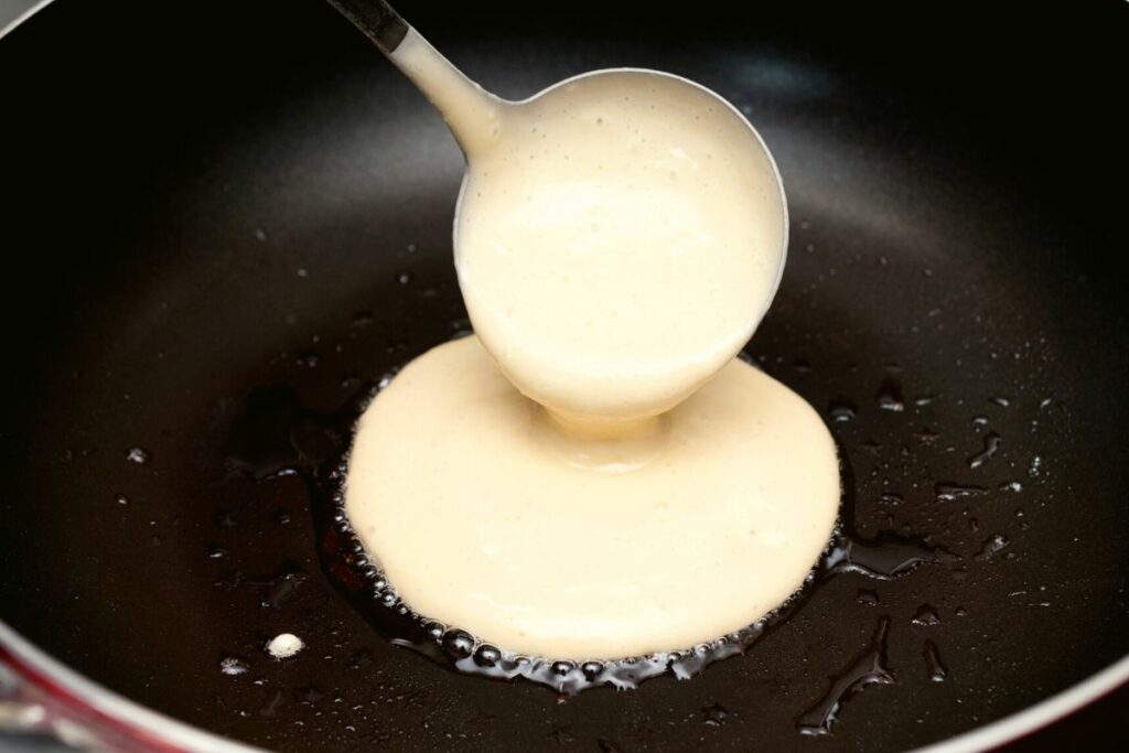 using a ladle to pour the batter in a pan