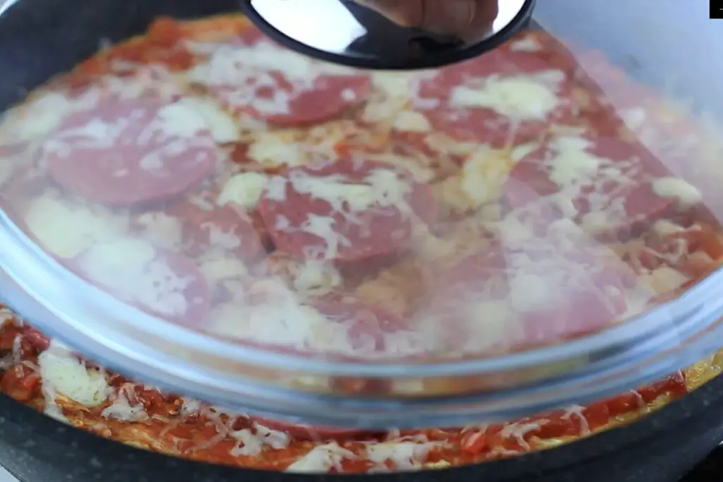 covering the pizza on the pan with a lid 