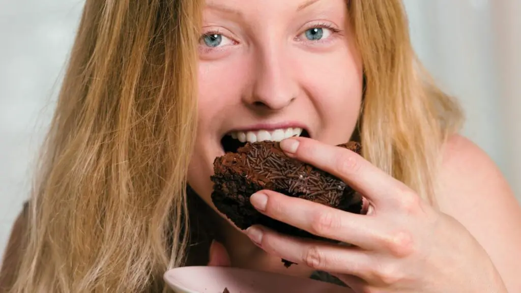 A woman is eating sweet potato avocado brownies