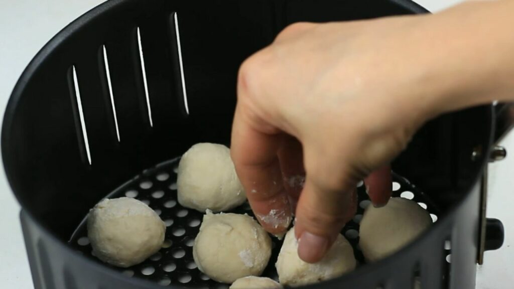 placing the donut balls in the air fryer basket