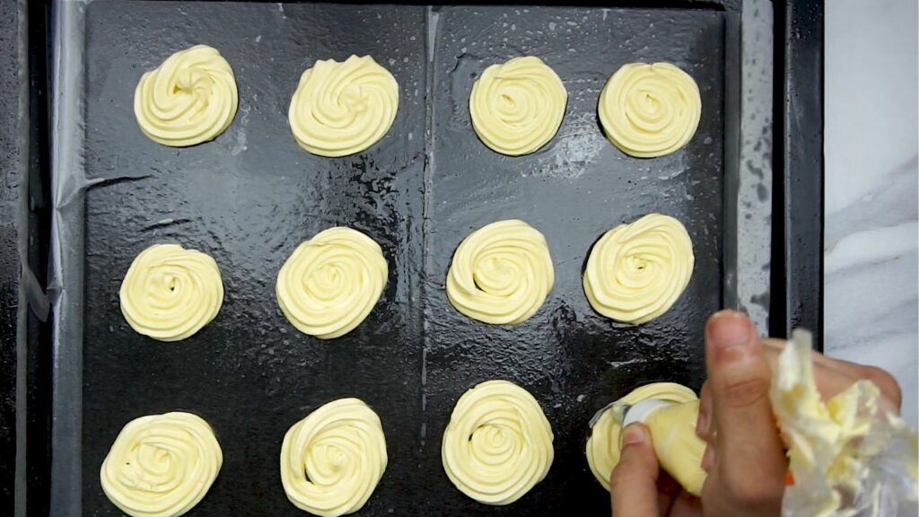 piping shortbread cookies onto a cookie sheet 