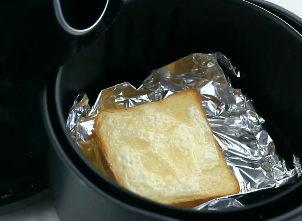 flipping the grilled cheese sandwich in the air fryer basket