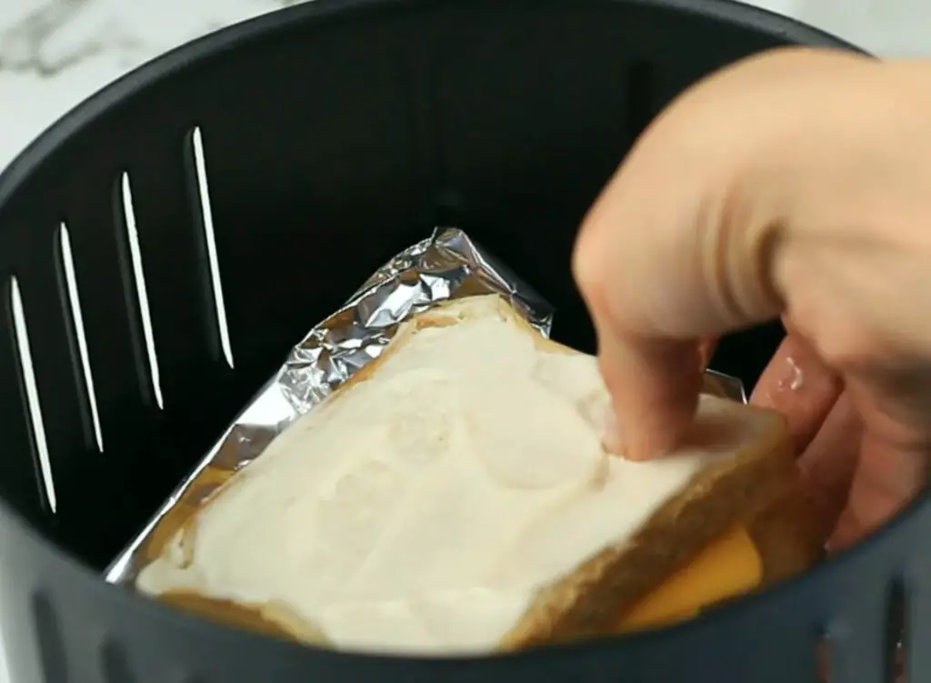 placing the sandwich in the air fryer basket