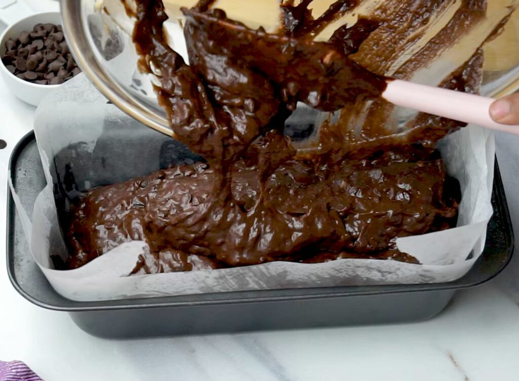 pouring the double chocolate banana bread batter into the loaf pan