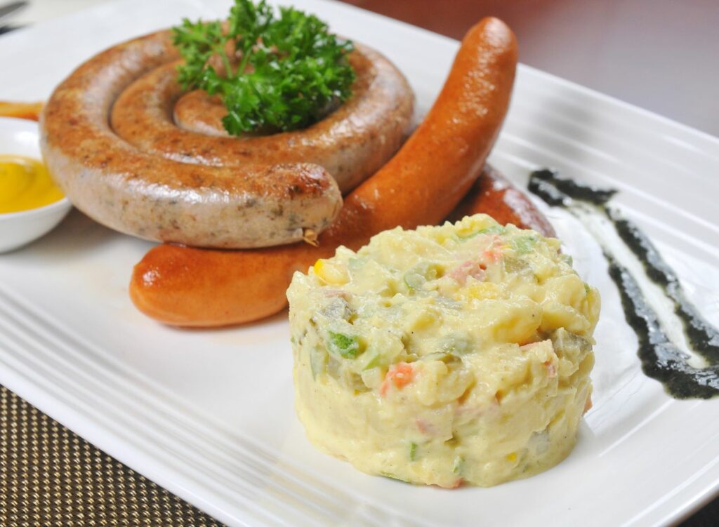 serving potato salad with sausages for dinner party  