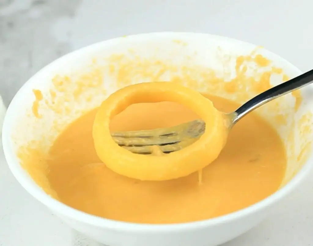 tipping the onion rings in egg mixture batter