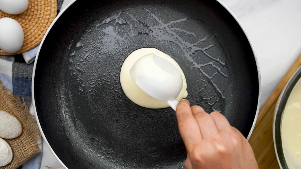 scooping the pancake batter into the hot pan