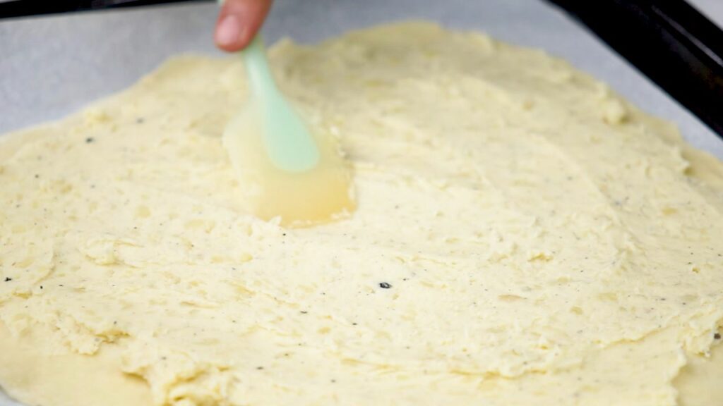 spreading the creamy potato filling on the dough