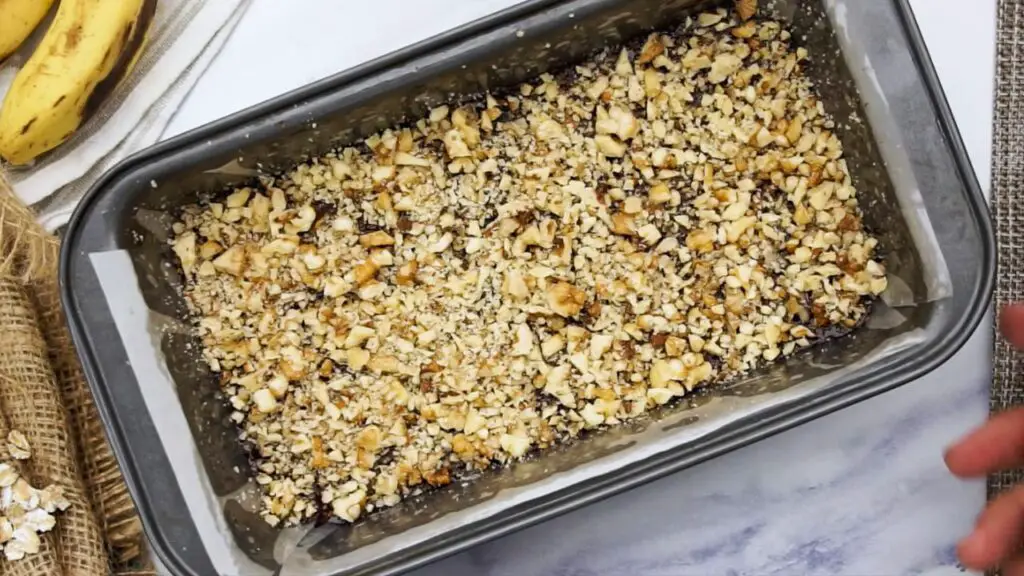 sprinkling crushed hazelnuts on top of the oat banana cake