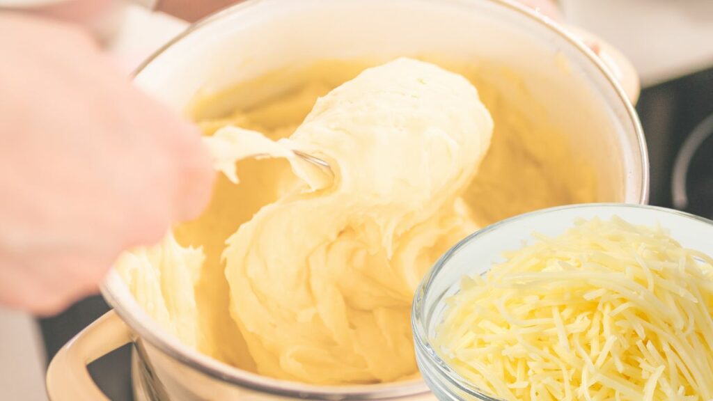 adding grated cheese to mashed potatoes