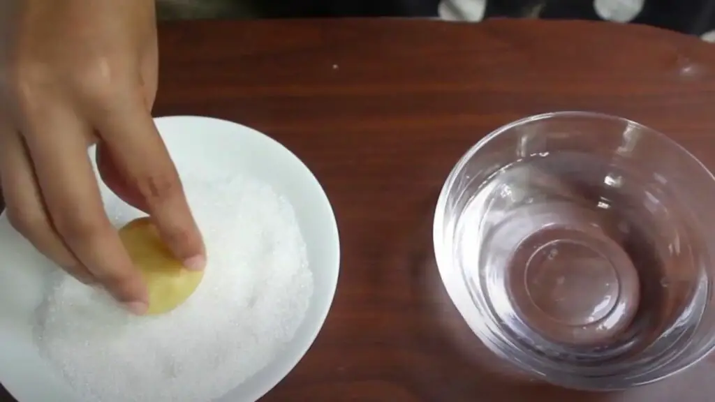 dipping the top side of the cookie into the water and into the sugar