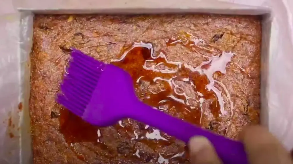 disributing the coconut treacle or syrup on the surface of the batter using the spatula