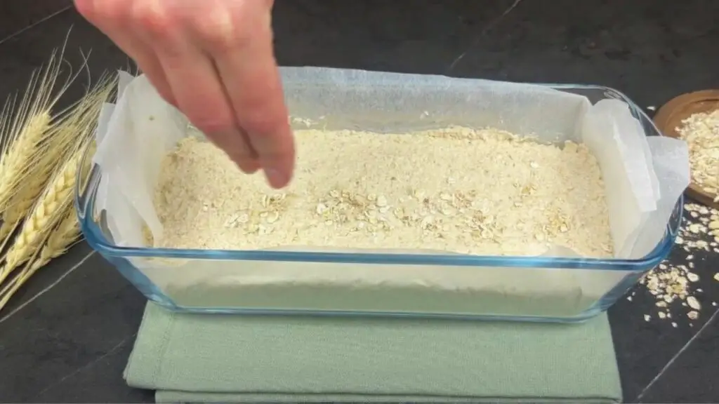 sprinkling oats on top of the dough
