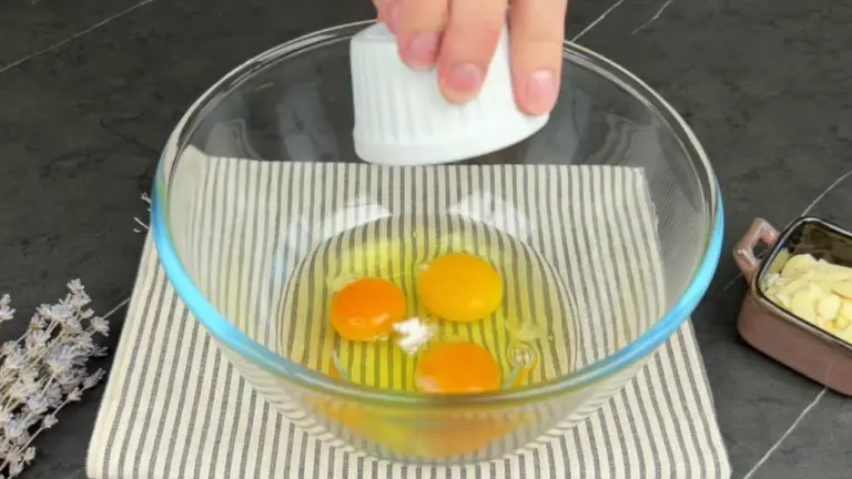 adding salt to a bowl of three eggs