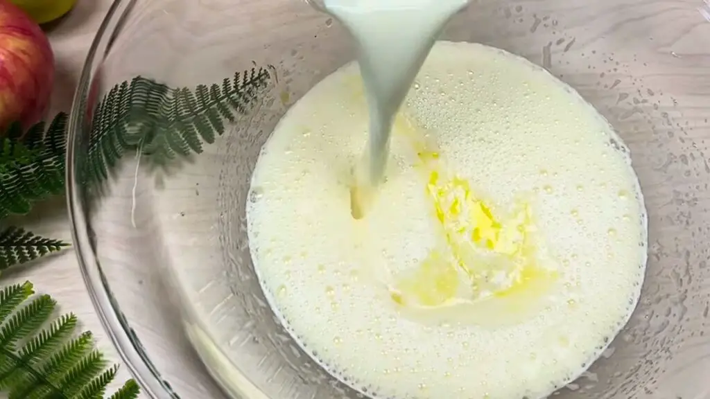 Milk being poured into a mixing bowl with melted butter, showing an early step in making apple cinnamon batter for a moist apple loaf cake.