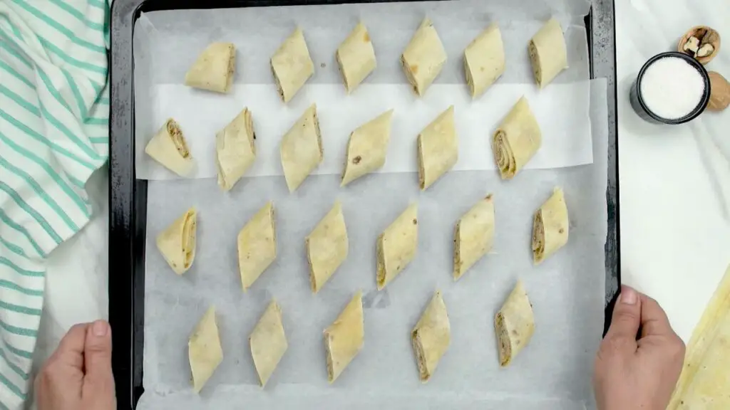 Baklava pieces arranged with space between them on a parchment-lined baking sheet so they bake evenly, shown as part of a dry baklava recipe