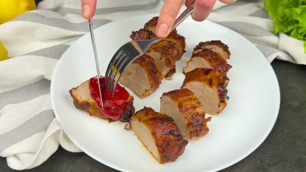 Juicy pork tenderloin air fryer slices with a caramelized glaze on a white plate
