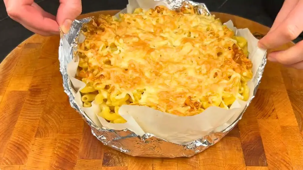 Placing ham and cheese slices over pasta in an air fryer basket for an air fryer pasta 