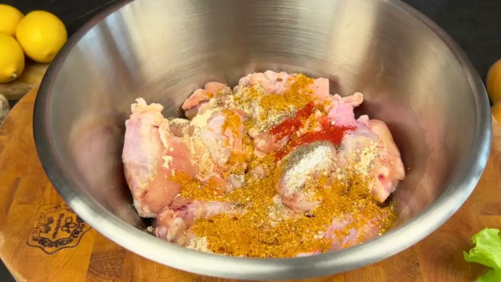 Raw chicken wings in a metal bowl coated with spices and seasonings, showing how do you make crispy wings in an air fryer.
