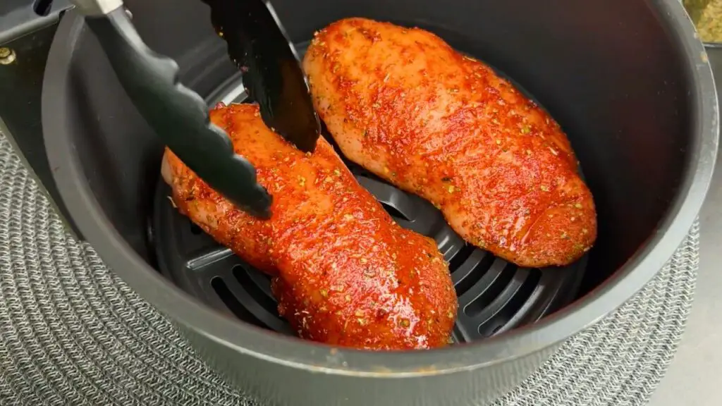 Seasoned chicken breasts placed in a Ninja air fryer for cooking chicken breast evenly and efficiently.