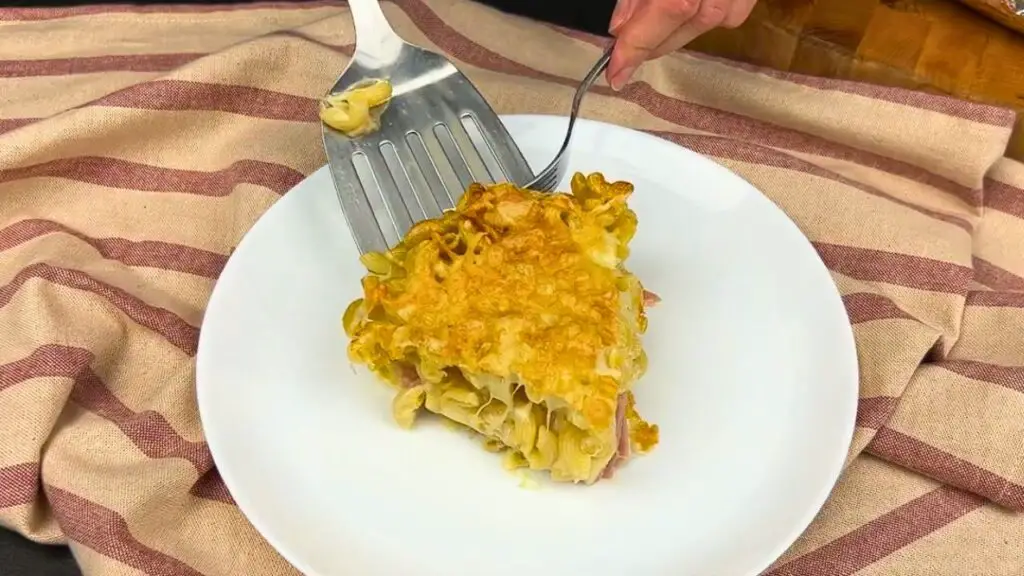 Serving a slice of cheesy pasta bake onto a plate, an air fryer pasta bake for easy weeknight meal.