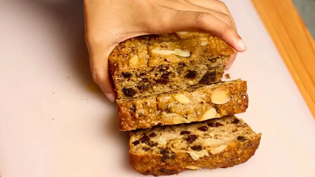 sliced of moist loaf cake filled with dried fruit and nuts on a cutting board, revealing soft layers of a healthy oatmeal breakfast cake