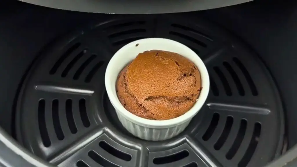 baked brownie inside an air fryer basket, perfectly risen and cracked on top, for a single serve brownie recipe.