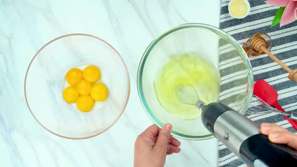 egg whites being whipped in a glass bowl next to egg yolks, preparing low carb pancakes