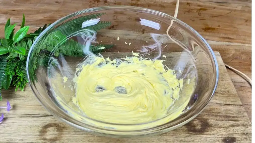 Butter is being beaten in a glass bowl until light, soft, and fluffy for a moist date cake recipe.