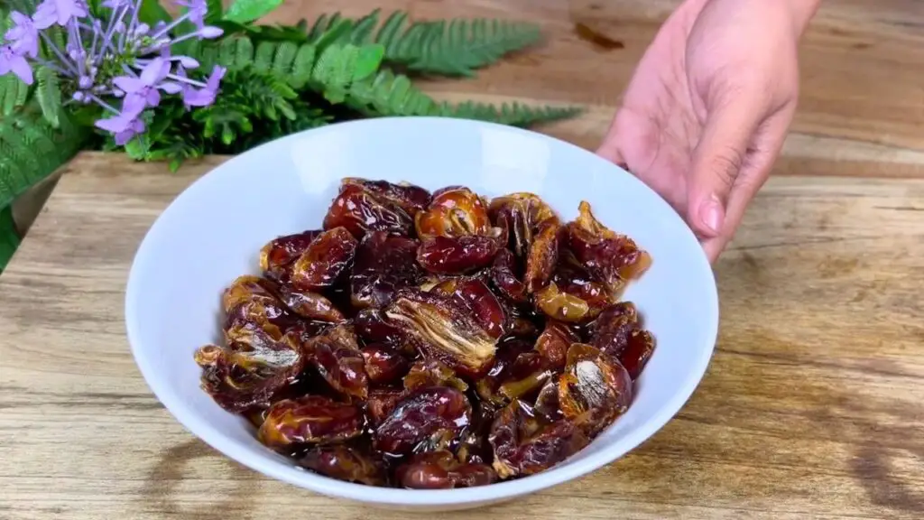 Chopped pitted dates soaking in water with baking soda in a bowl, softening to create a moist texture for this date cake recipe.