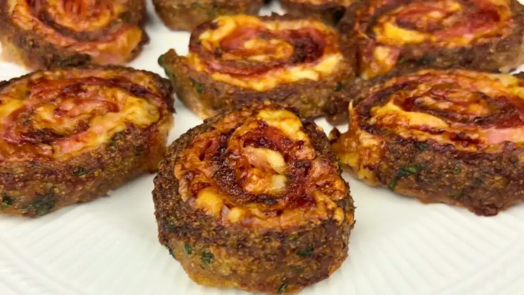 Cooked sliced meatloaf rolls with melted cheese and ham spirals, golden and crispy on a plate, ready to serve as air fryer meatloaf.