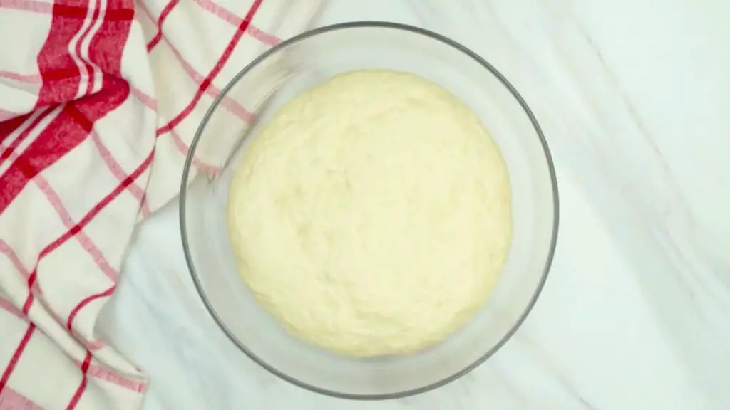 Easiest croissant recipe step showing a glass bowl with risen dough that has doubled in size, appearing puffy and airy after restin