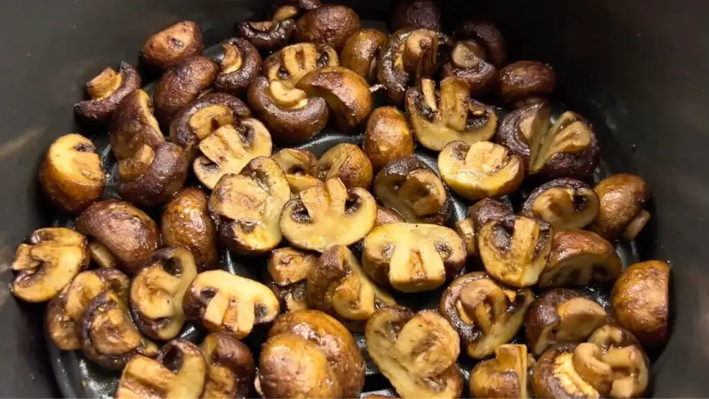 air fryer garlic mushrooms in a basket, with perfectly browned and tender mushrooms.