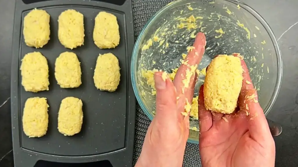 Chicken nuggets step showing hands shaping the mixture into nugget forms beside a tray of evenly shaped raw chicken nuggets ready to cook.
