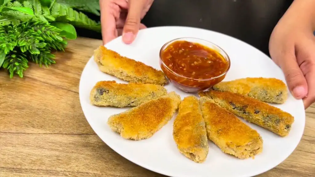Crispy fish bites served on a plate with dipping sauce, showing golden fried sardines ready to eat.