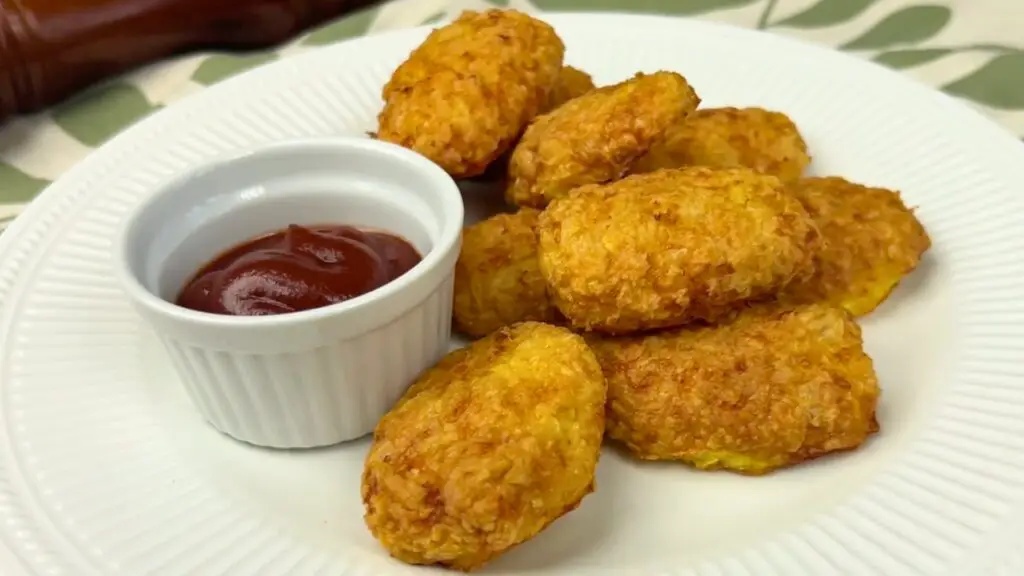 Crispy homemade chicken nuggets served on a white plate with ketchup dipping sauce, perfect for easy meal serving ideas.