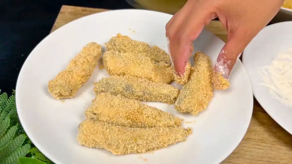 How to cook canned sardines step showing sardines coated with breadcrumbs on both sides, gently pressed so the coating sticks without breaking.