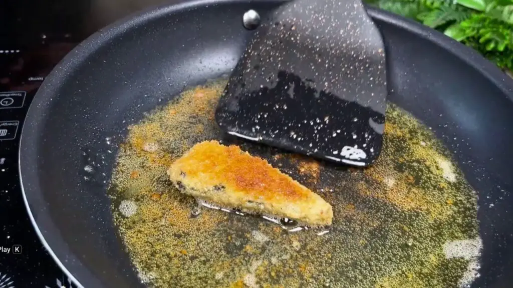 Reheating crispy sardines in a frying pan over medium-low heat until warm and lightly crisp again.