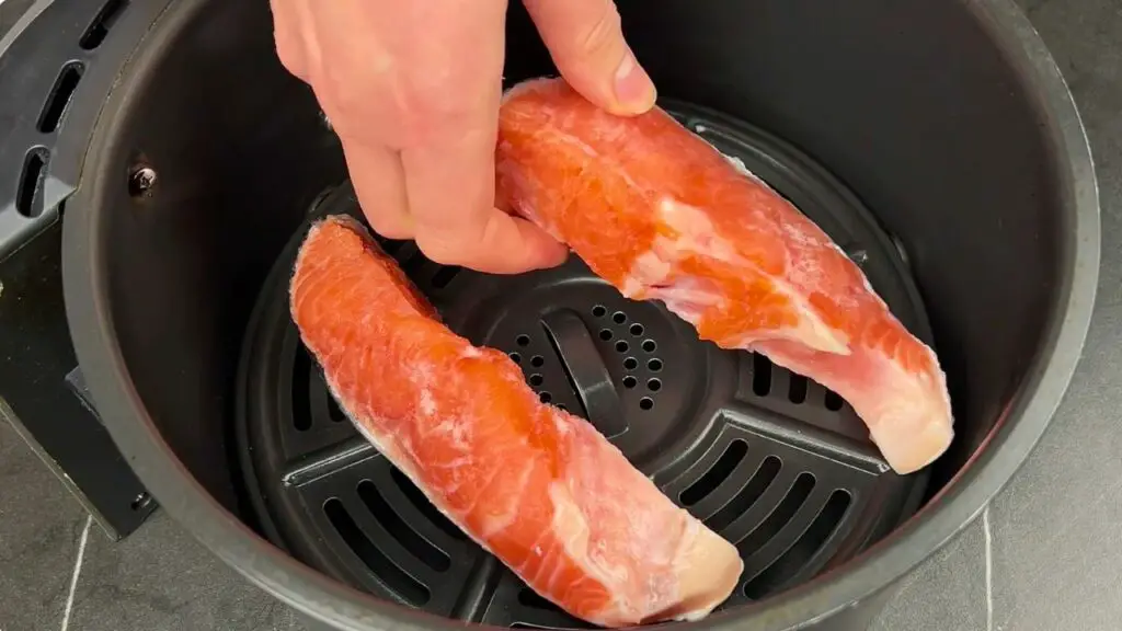 Air fryer frozen salmon placed skin side down in the air fryer basket before cooking at 375°F for 7 minutes.