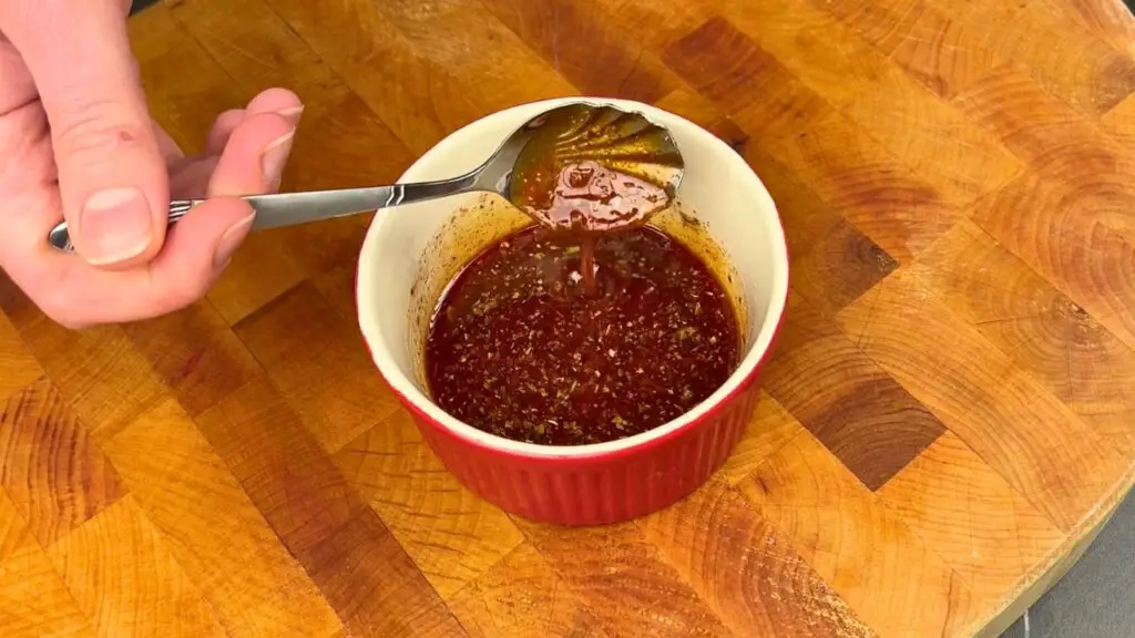 Air fryer salmon recipe step showing olive oil and seasonings mixed in a small bowl for salmon seasoning.