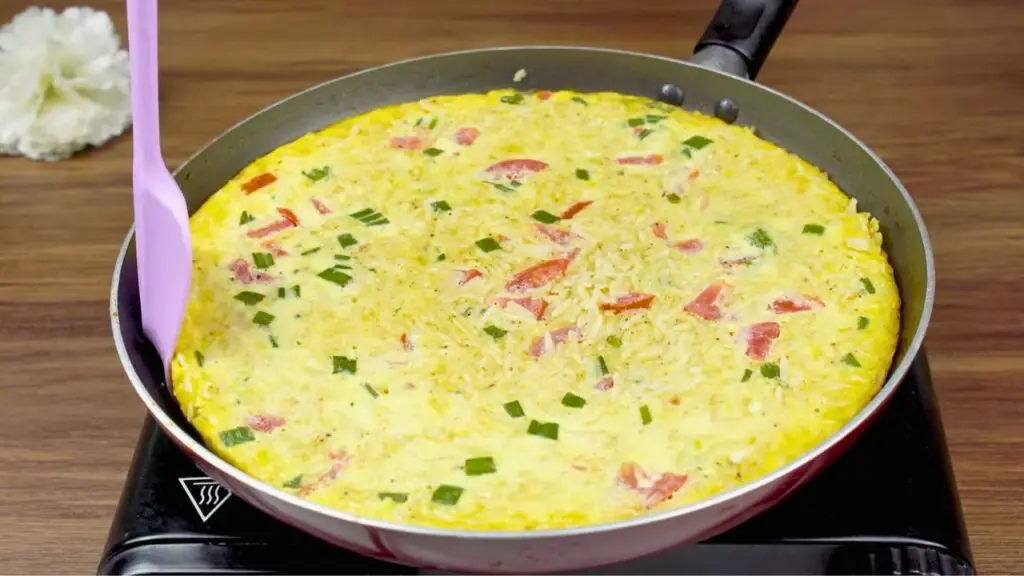 Egg and rice mixture cooking in a pan for a simple egg and rice recipe until firm and fully set.