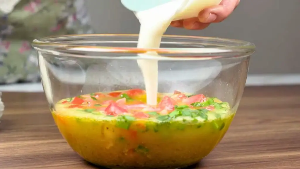 Egg mixture with yogurt, tomatoes, and leeks being prepared for a rice and eggs recipe.